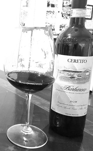 A bottle of Barbaresco wine next to a glass of the wine on a table