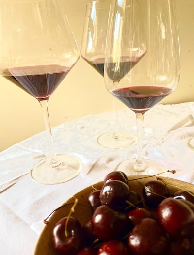 A bowl of cherries and three glasses of red wine