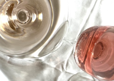 Two glasses of rosé wine with different shades of pink on a white tablecloth