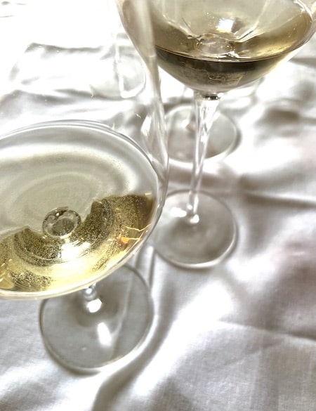 Two glasses of white wine one golden and the other pale straw on a white tablecloth